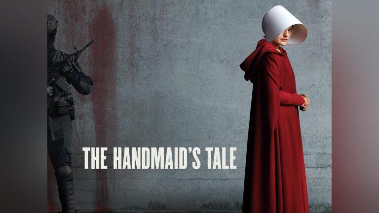 Ein Charakter aus 'The Handmaid's Tale' in einem roten Kleid mit einer weißen Haube, vor einer grauen Wand stehend.
